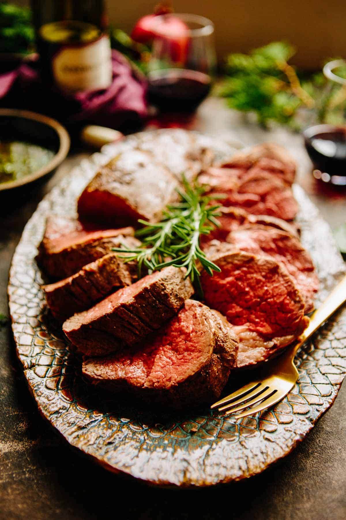 Slices of beef tenderloin on a platter with a gold fork.