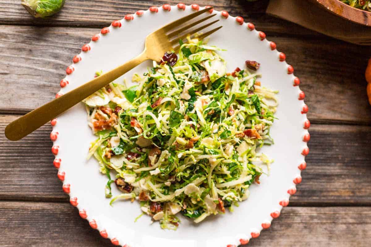 Close up of a white plate with salad and a gold fork.