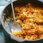 A close up of a dish of cauliflower au gratin with a spoon inside.