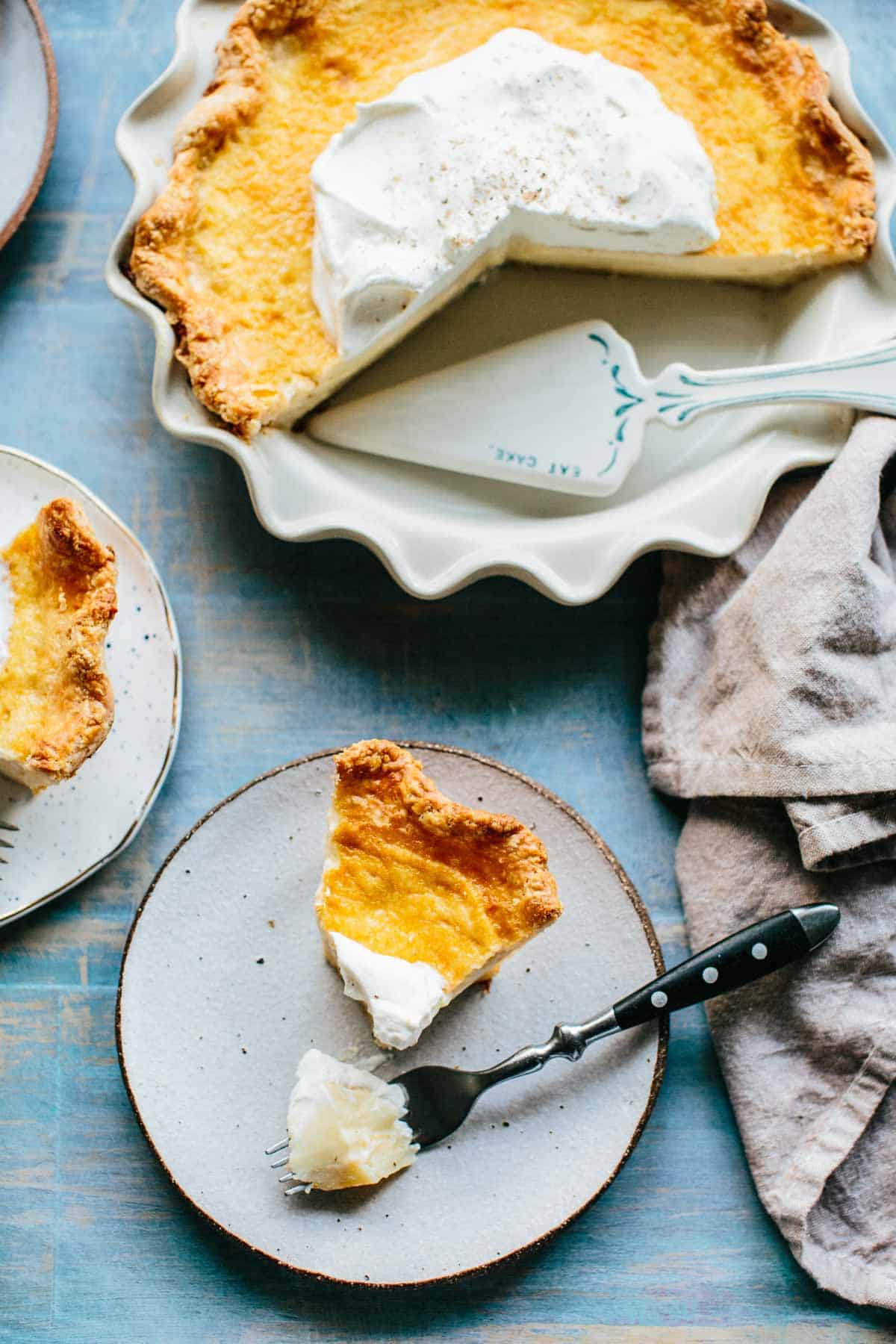 Top view of a pie with slices removed and a plate with a slice and a fork.