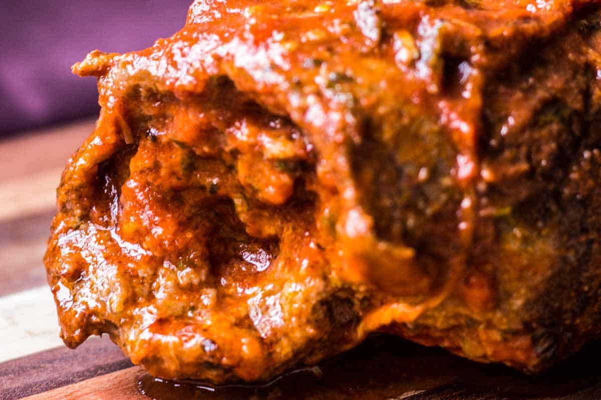 An extreme close up of the side of a whole beef braciole rolled up.