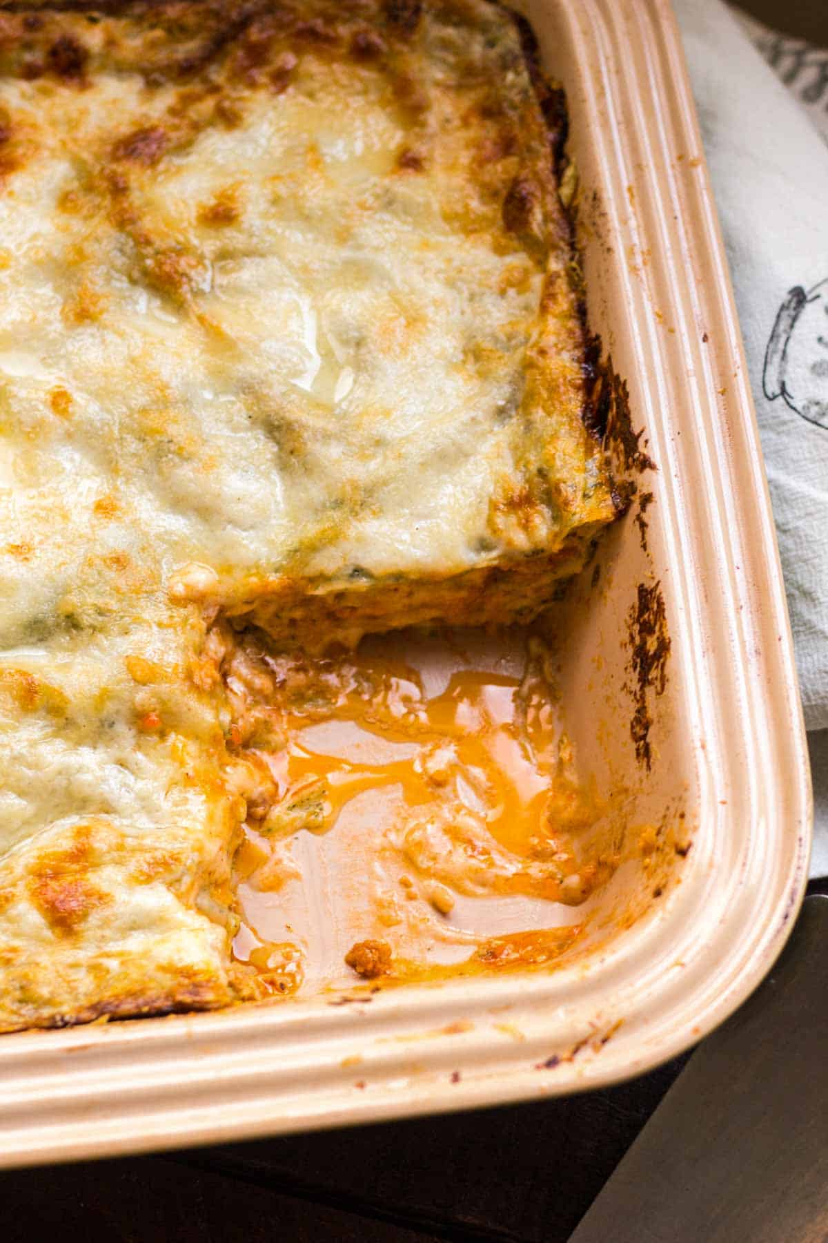 Top view of a baking dish of lasagna missing the corner slice.