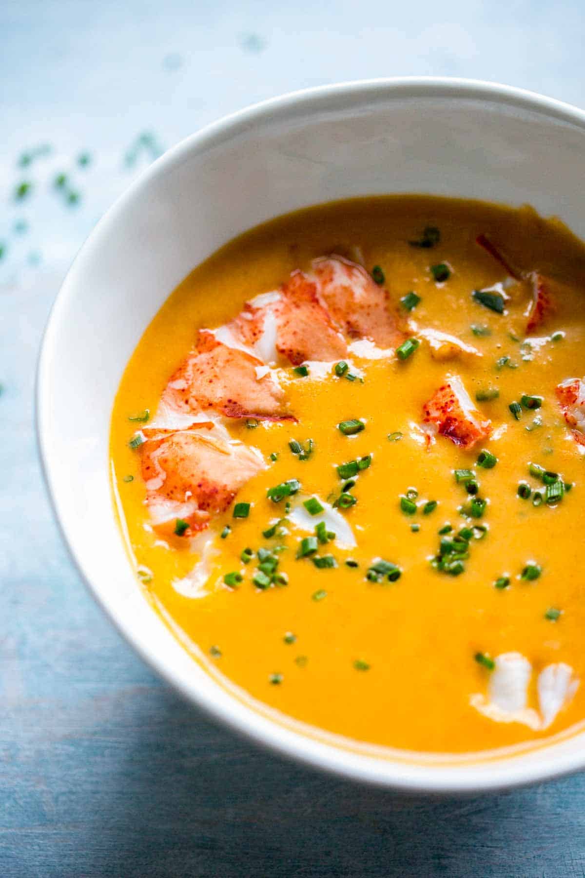 Close up of a bowl of lobster bisque wtih a lobster tail on top.