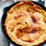 A close up of a Dutch baby pancake in a cast iron skillet.