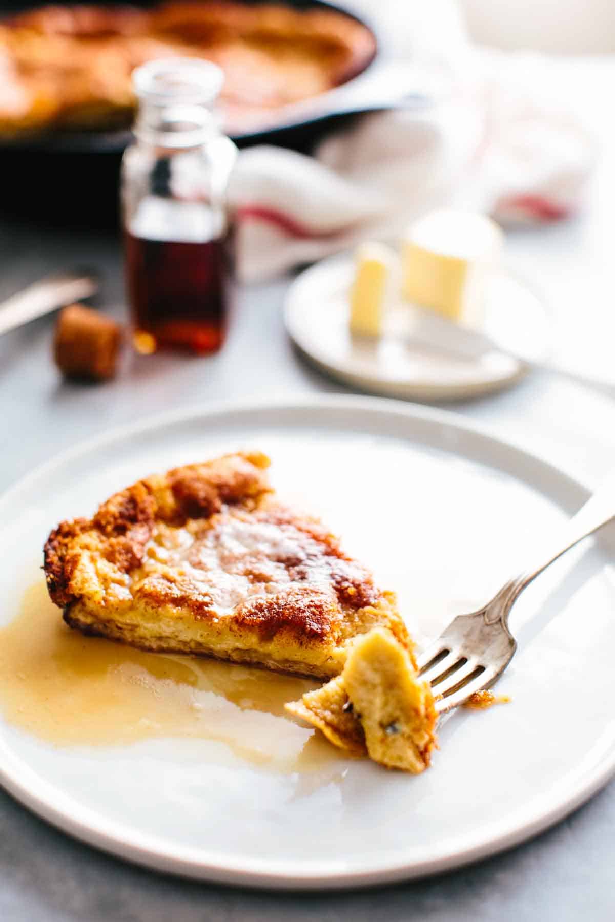 Close up of a German pancake slice with a fork and butter in the background.