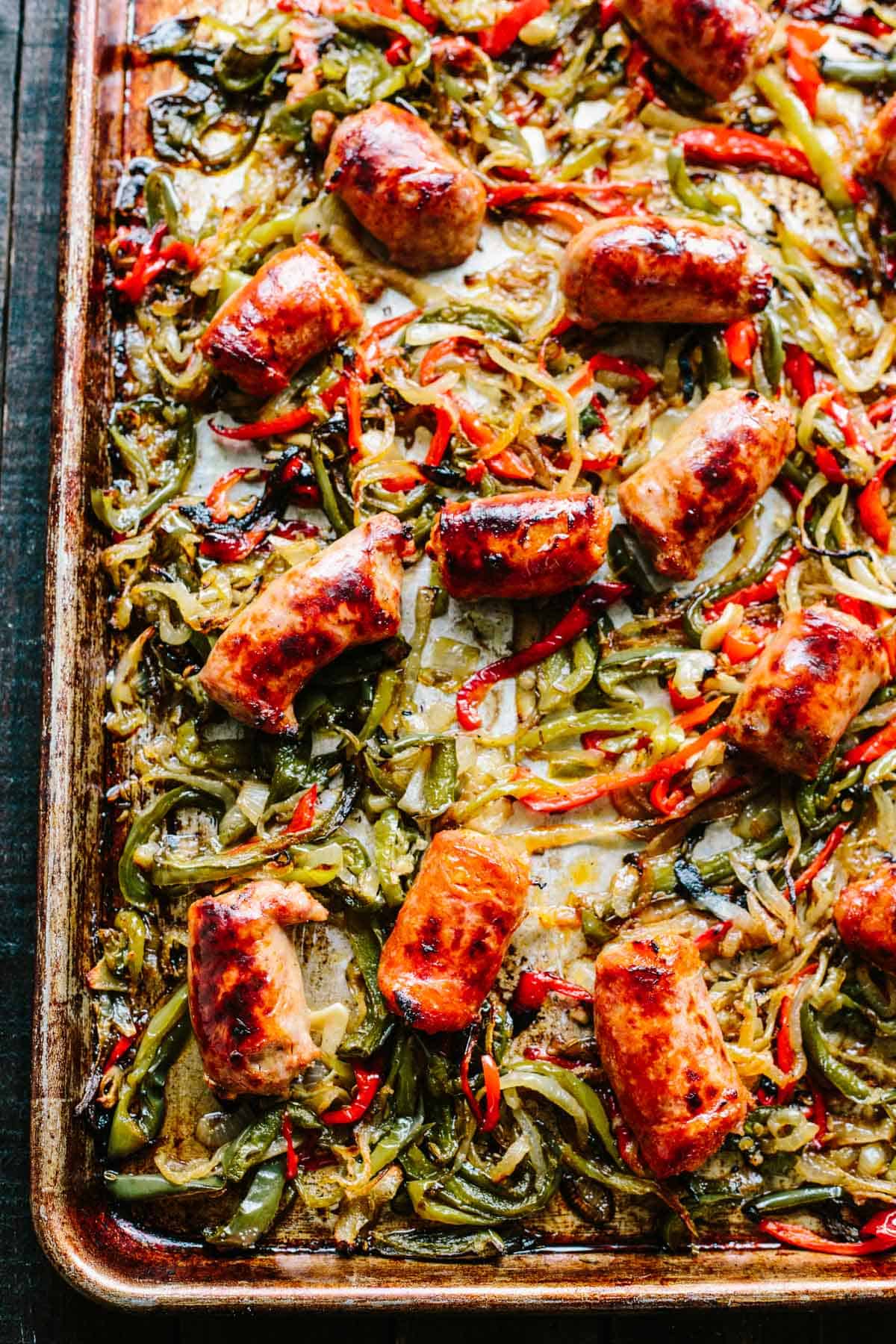 Overhead shot of a baking sheet with roasted Italian sausage, red and green peppers and onions. 