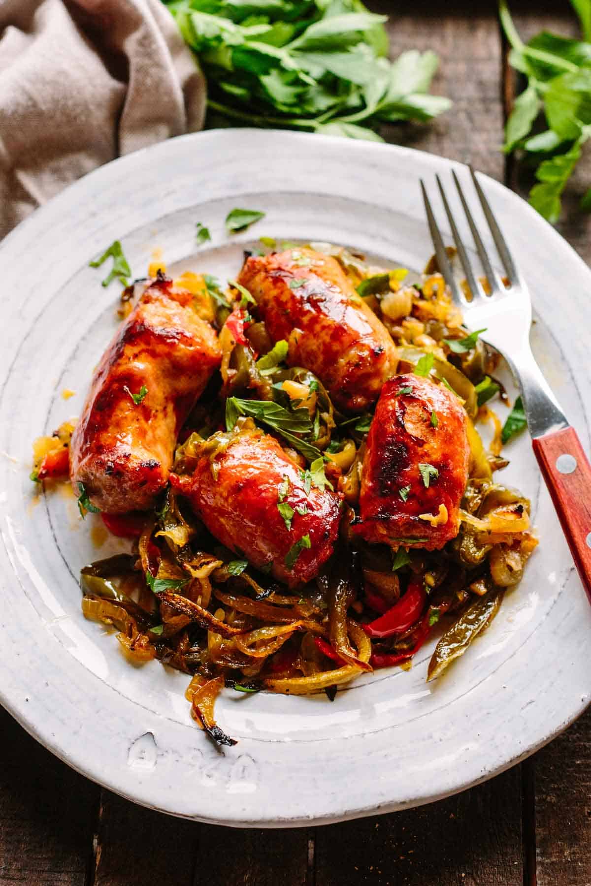 Close up of overhead shot of Italian sausage and peppers on a gray plate with a fork.