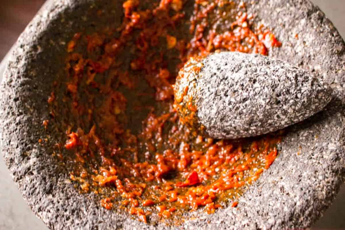 A mortar and pestle grinding chipotle peppers.