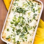 Overhead shot of a rectangular casserole dish with melted cheese and scallions on top.