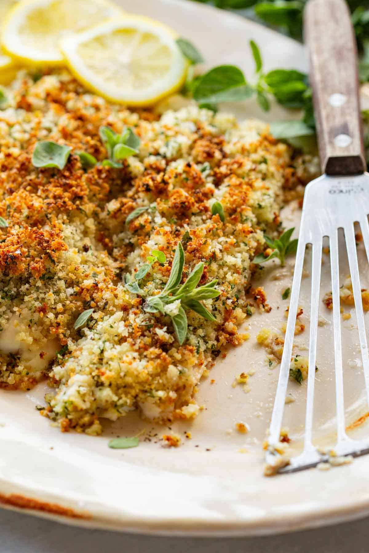 A plate of breaded fish with a fish spatula and one piece removed.