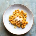 Plate of homemade sweet potato gnocchi topped with rosemary and parmesan.