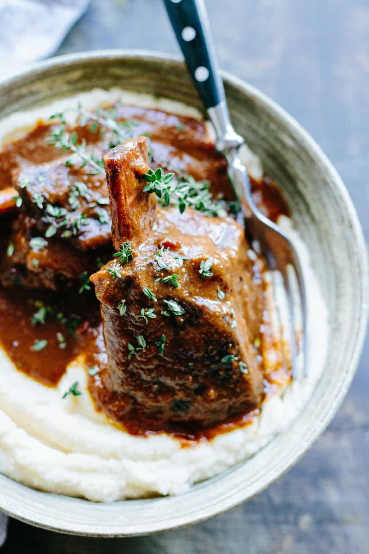 Herb-garnished beef short rib serving on a plate.