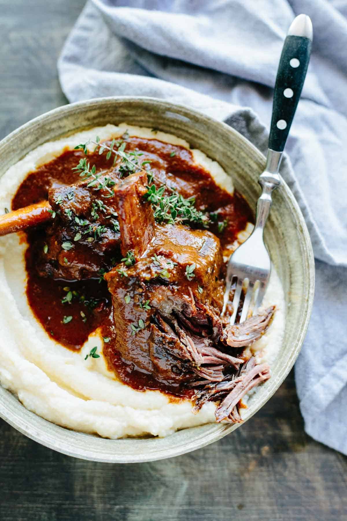 A fork cutting into a perfectly cooked braised short rib.