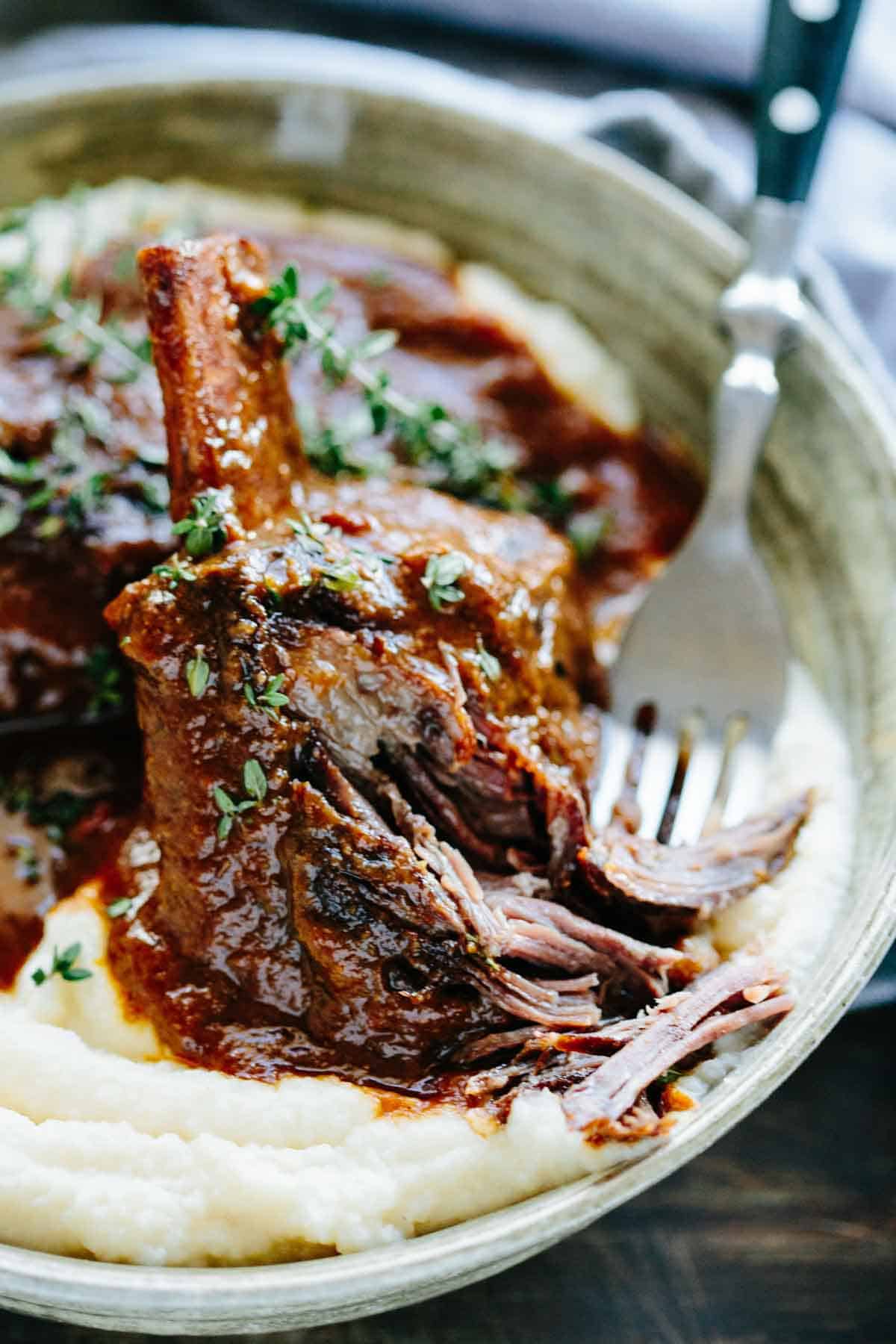 Scooping up a bite of beef short ribs with a fork.