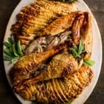 Overhead shot of carved turkey a platter with herbs.