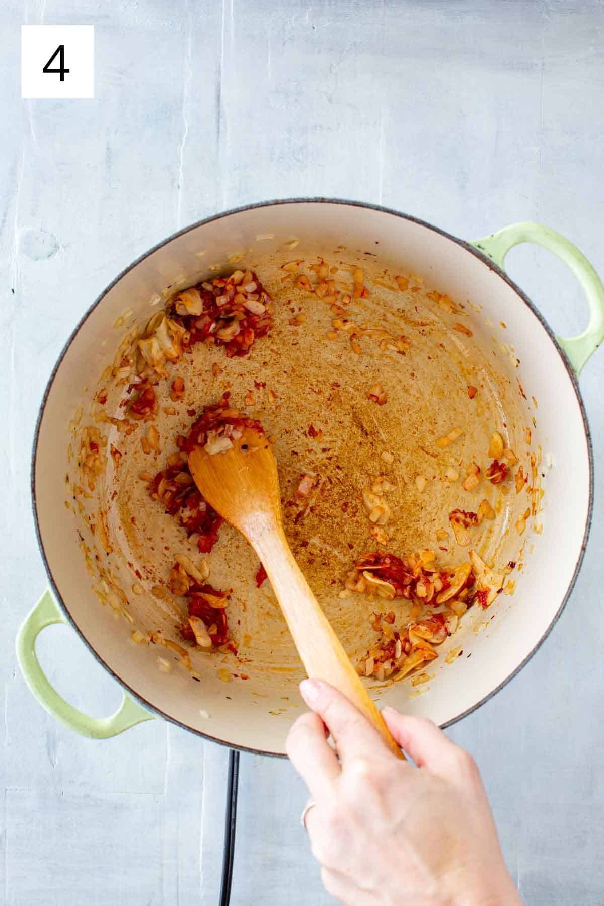 Stirring tomato paste into sautéed garlic and onions.