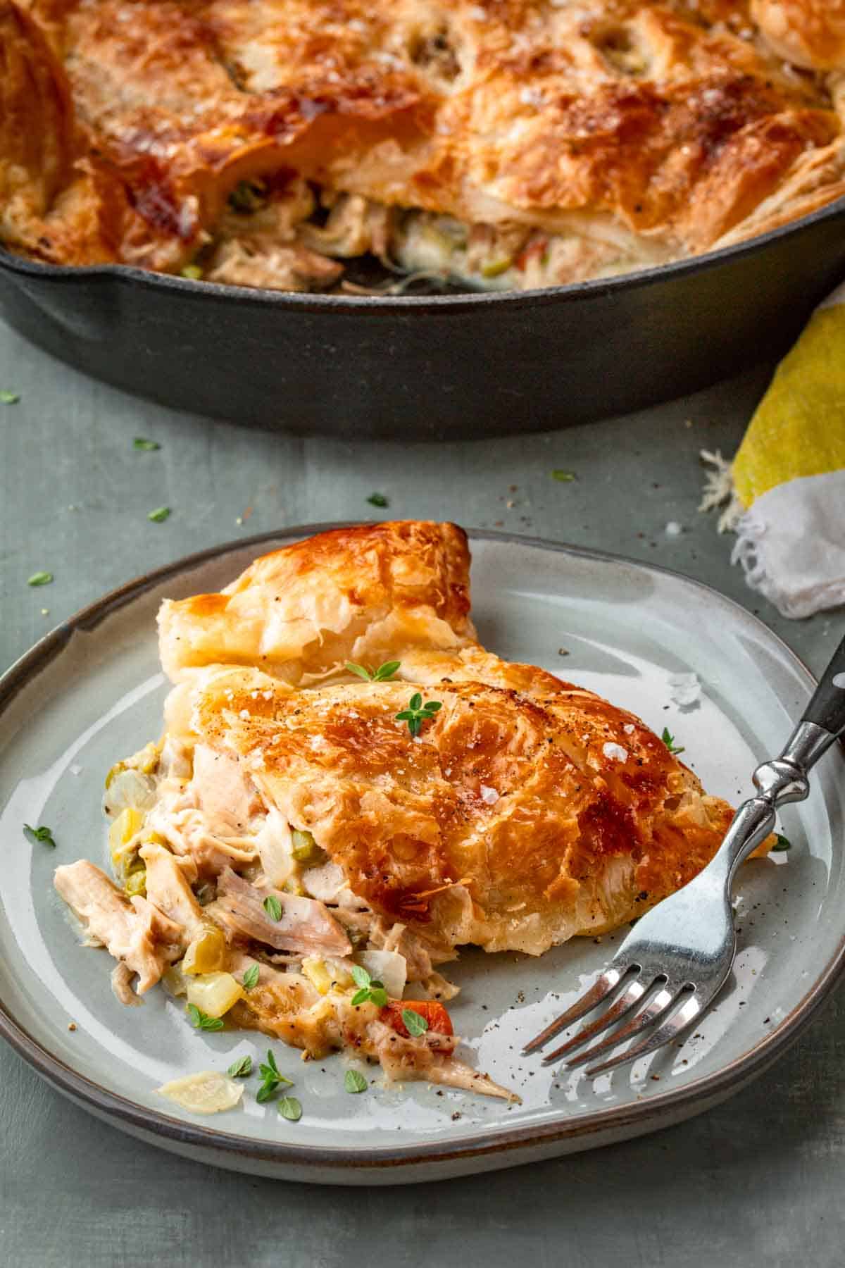 A gray plate with a piece of turkey pot pie and a fork.