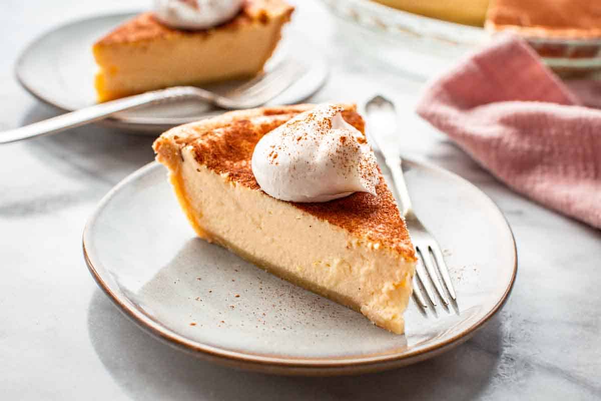 Slice of ricotta pie topped with homemade whipped cream.