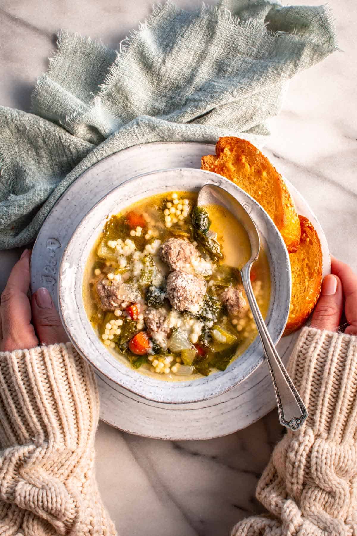 A bowl of Italian wedding soup with crusty bread. 