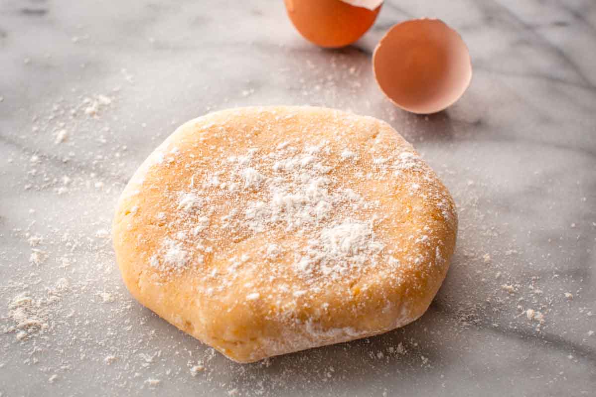 A disc of Italian shortcrust pastry dough on a marble board.