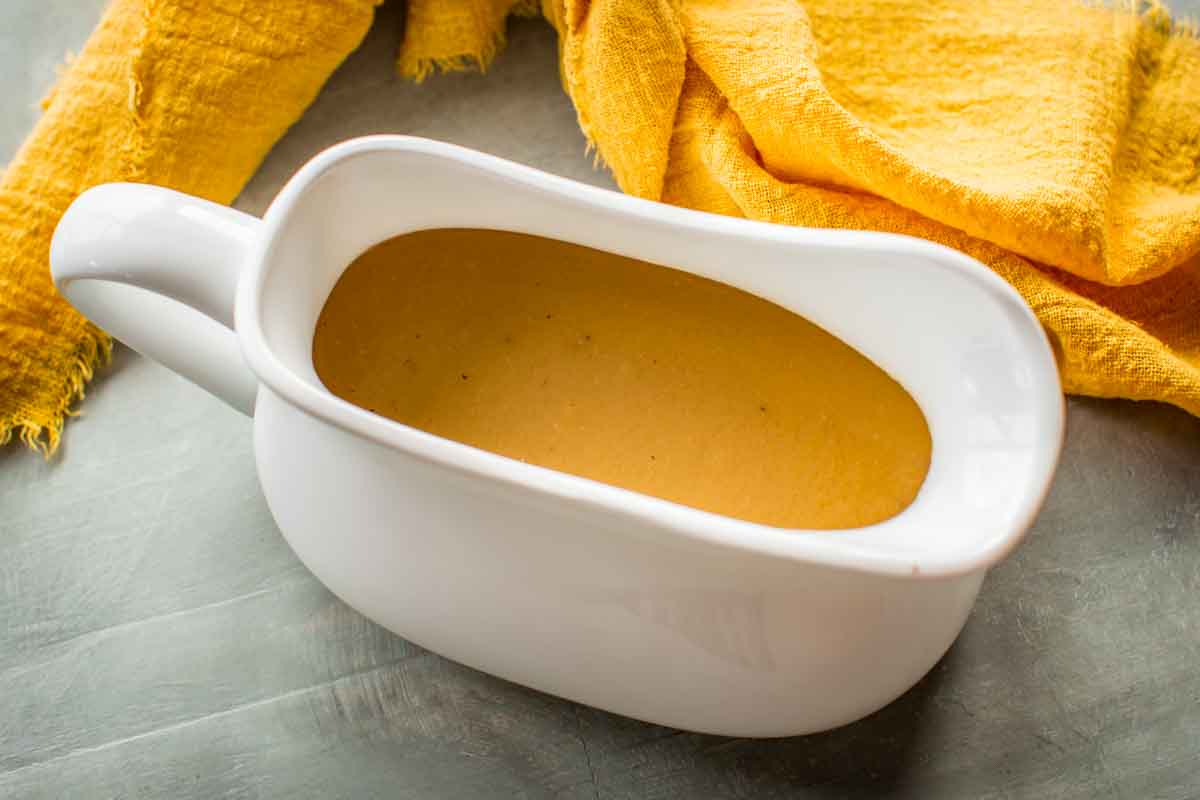 Gravy in a gravy boat with a yellow napkin.