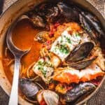 A large pot of San Francisco cioppino with a large serving spoon.