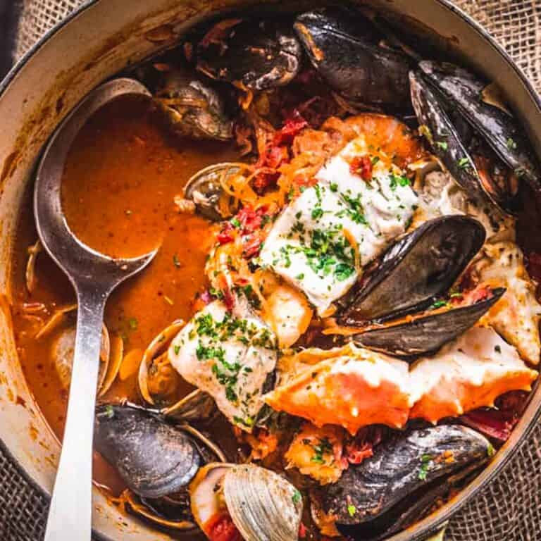 A large pot of San Francisco cioppino with a large serving spoon.