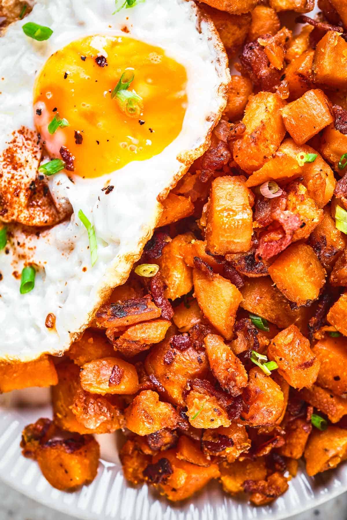 Close up of sweet potato hash with a runny fried egg.
