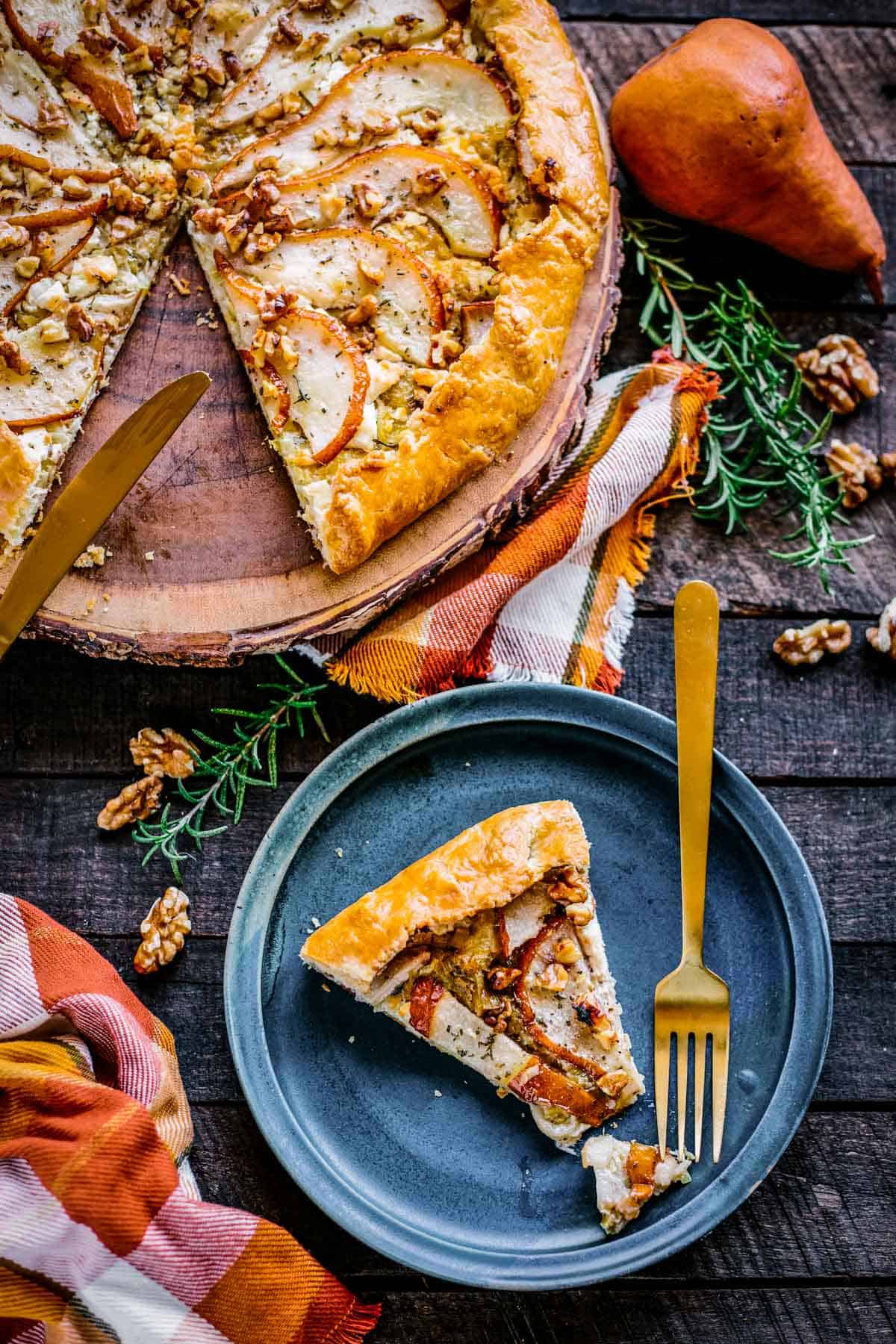 A pear galette with a slice cut out and set on a small blue plate.
