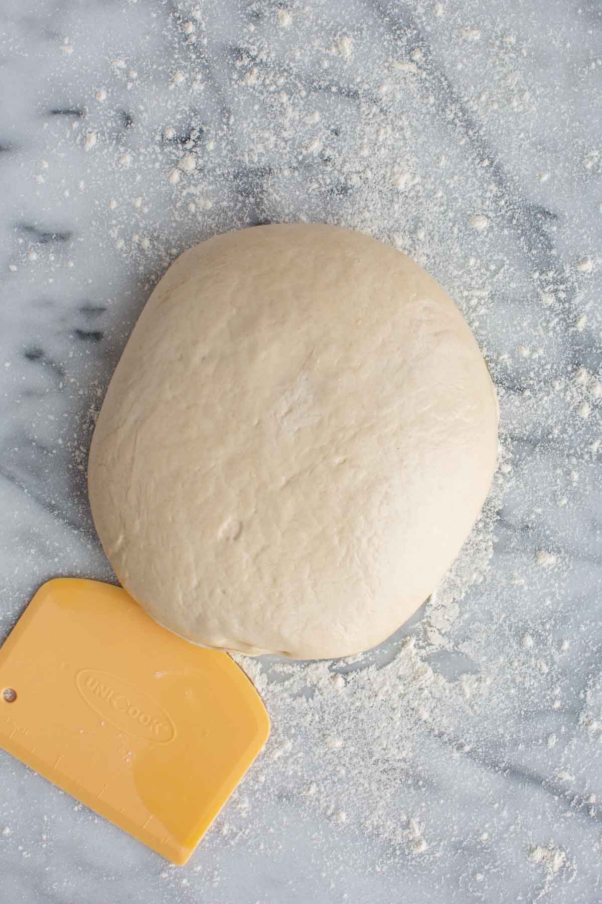 Large ball of pizza dough on a countertop.