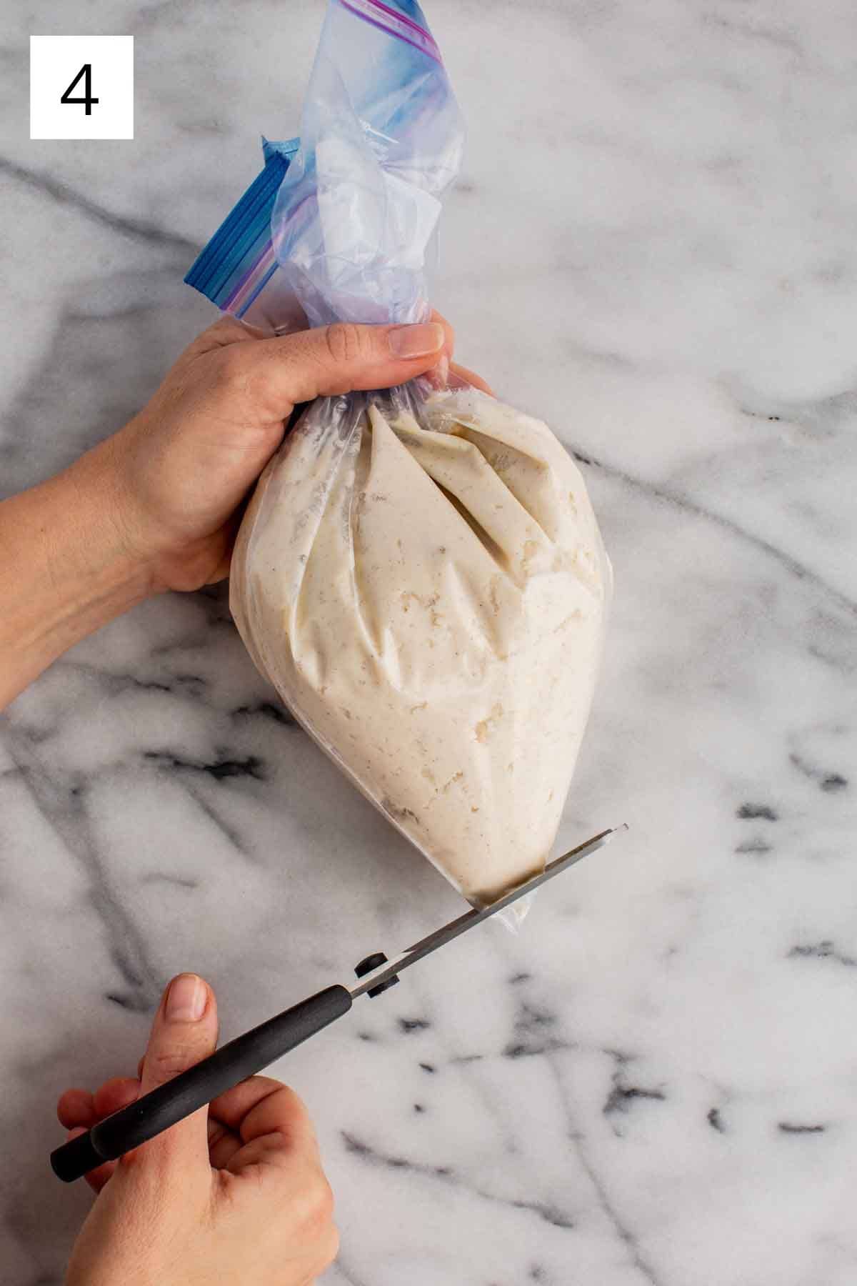 Snipping the corner of a zip top bag filled with cannoli cream.
