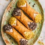 A light green tray of ricotta stuffed cannoli.