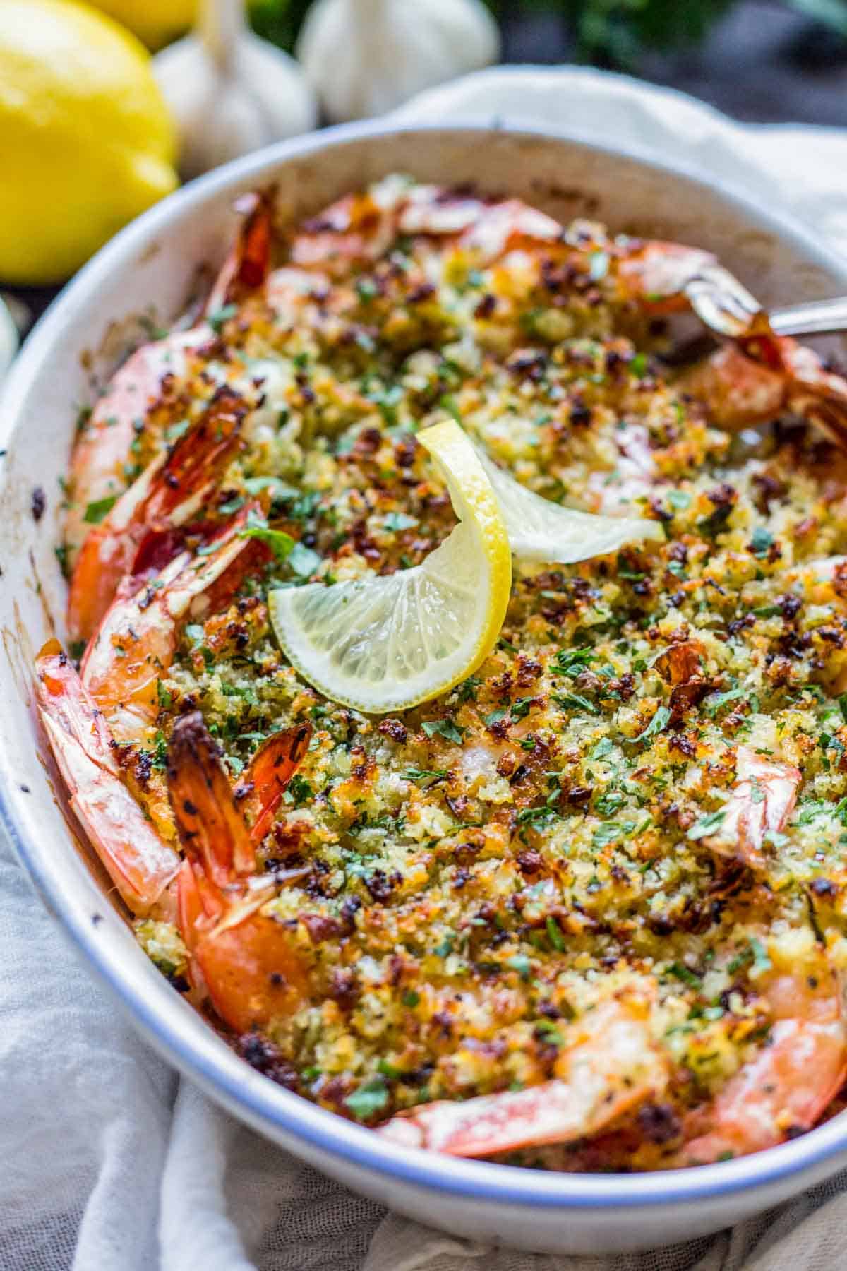 A gratin dish of baked shrimp with breadcrumbs and lemon.