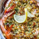 A spoon scooping out baked shrimp scampi from a dish.