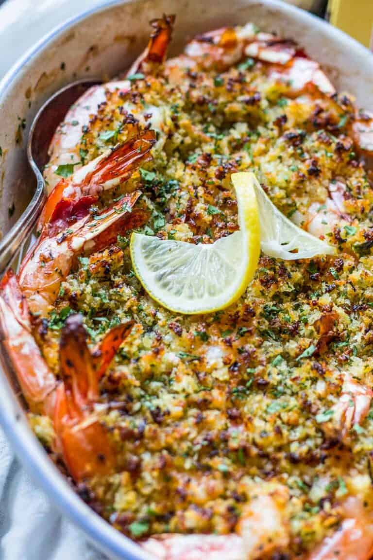 A spoon scooping out baked shrimp scampi from a dish.