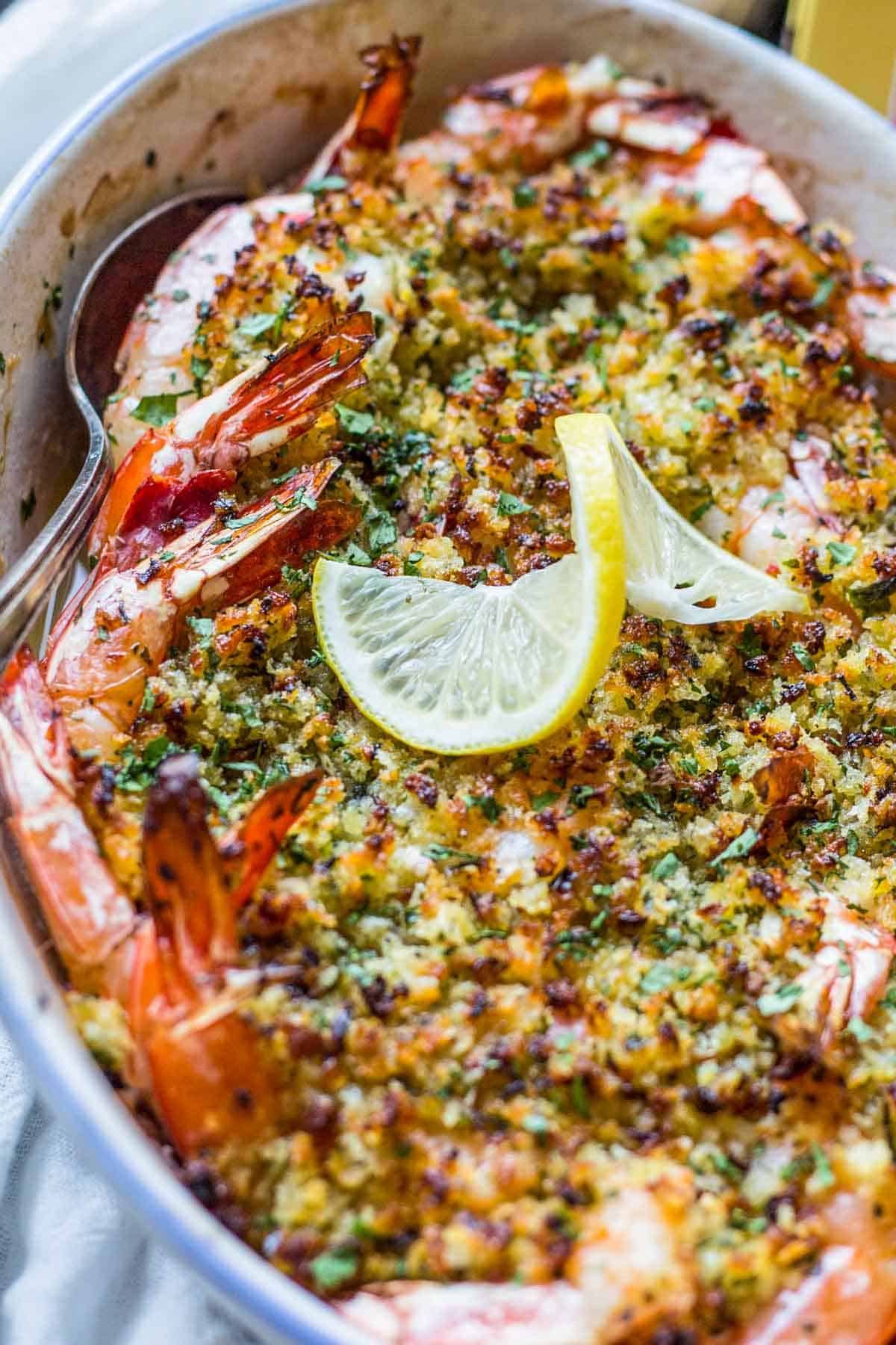 A spoon scooping out baked shrimp scampi from a dish.