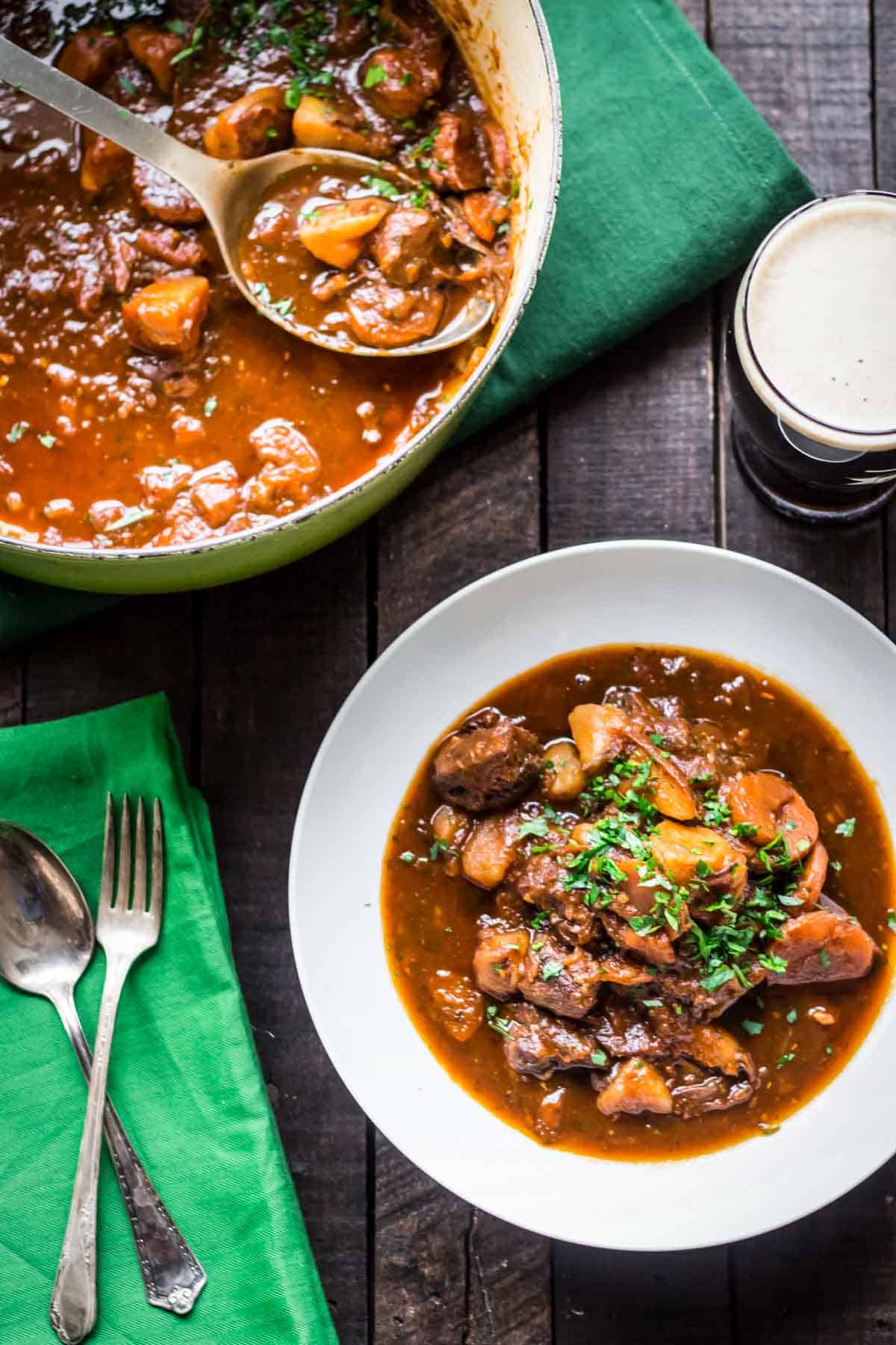 A soup bowl of Irish beef stew next to a filled cast iron pot.