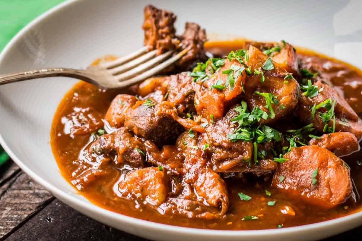 A fork in a bowl of beef and carrot Irish stew.