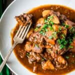 Awhite bowl of Irish stew with a fork.
