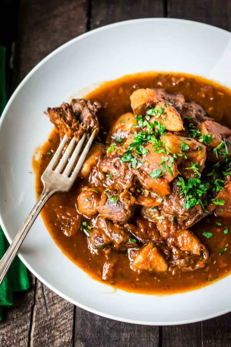 Awhite bowl of Irish stew with a fork.