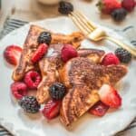 Three pieces of French toast on a plate with fresh berries.