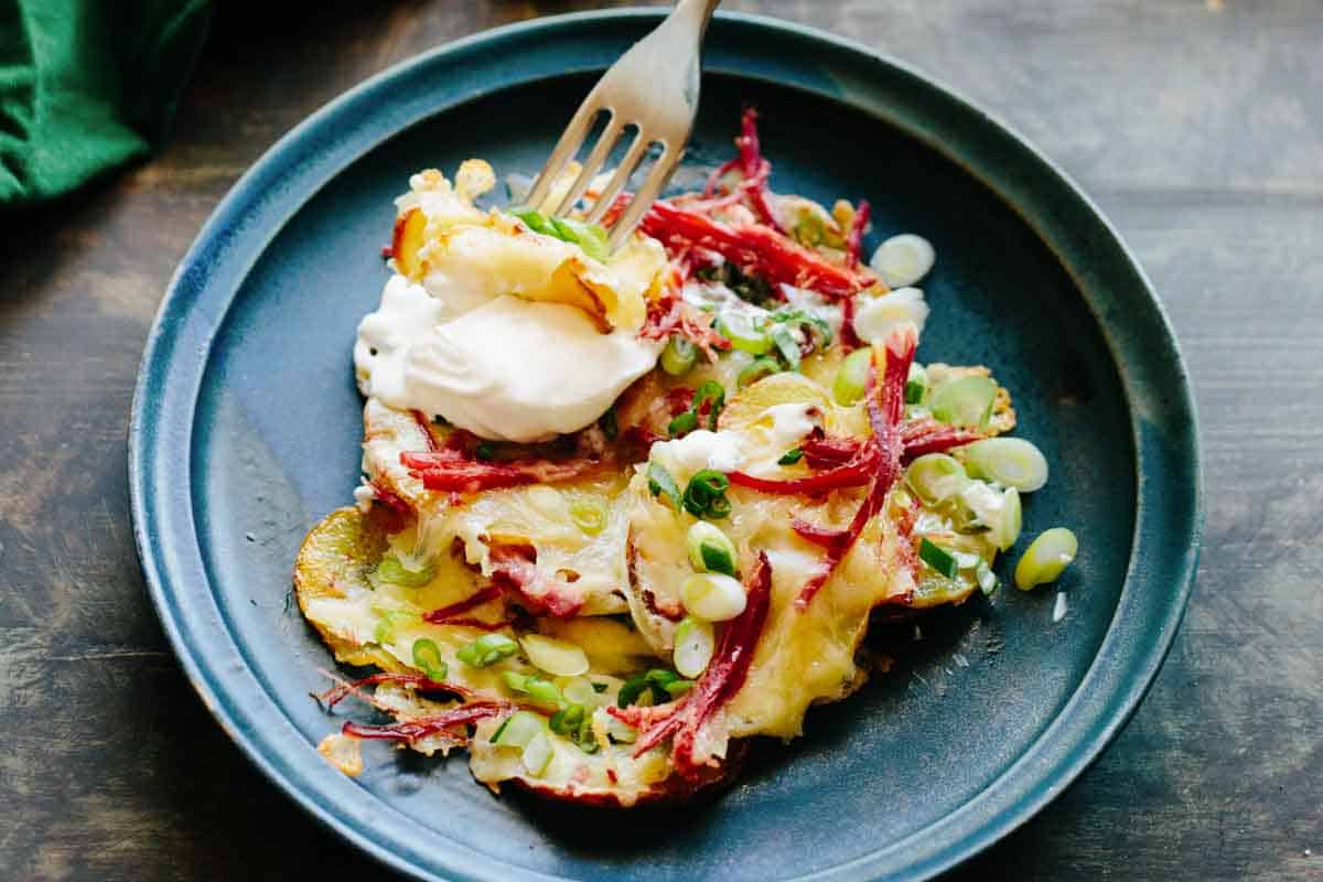 A fork digging into a dinner plate full of Irish nachos.