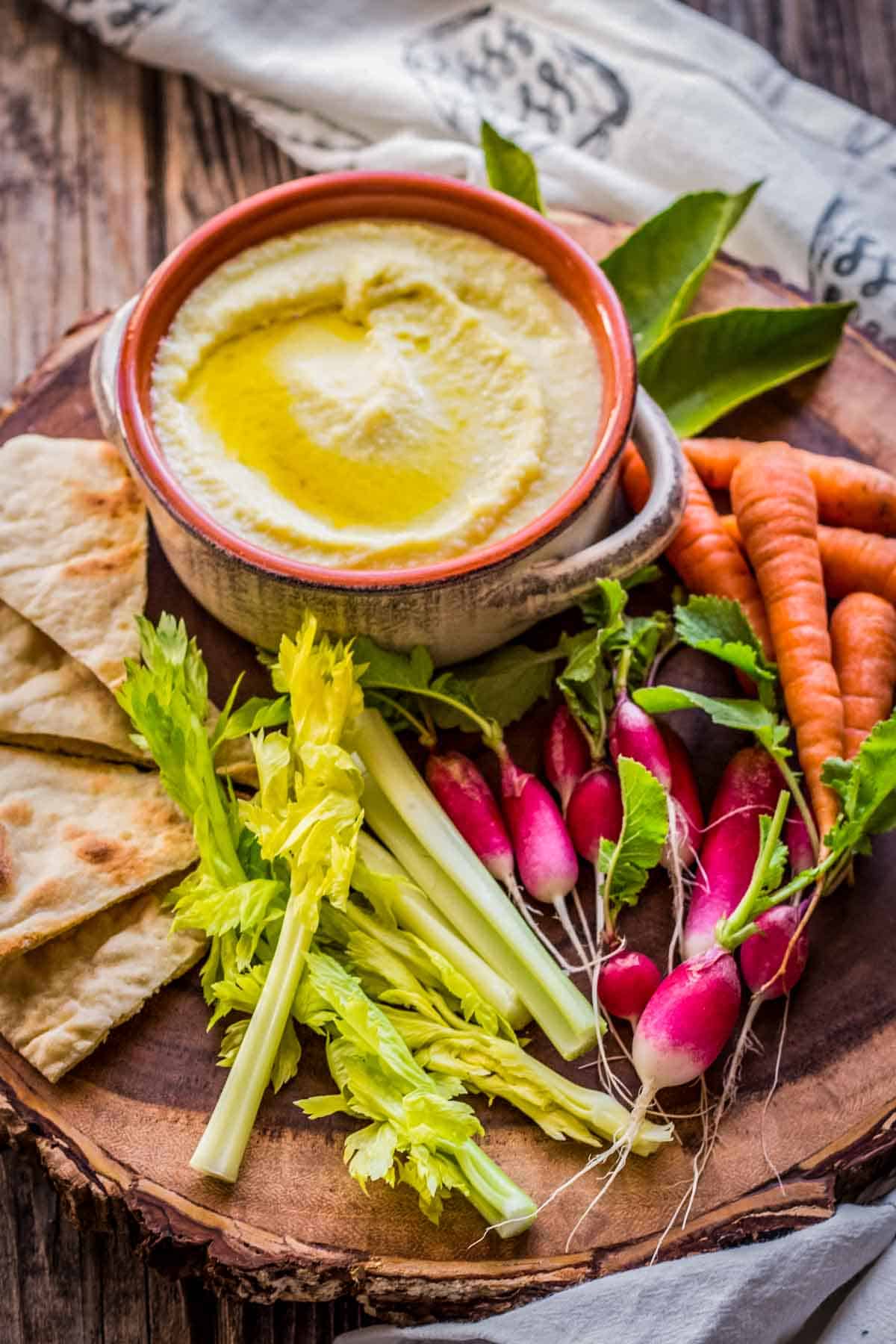 A small stone bowl of skordalia among fresh veggies and pita points.