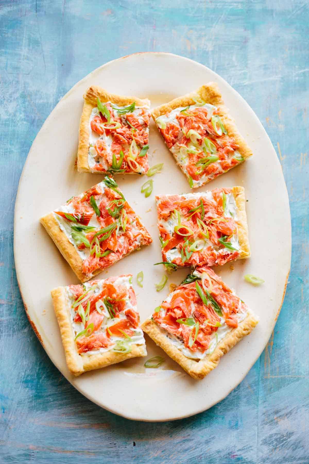 A platter with smoked salmon tart cut into squares.