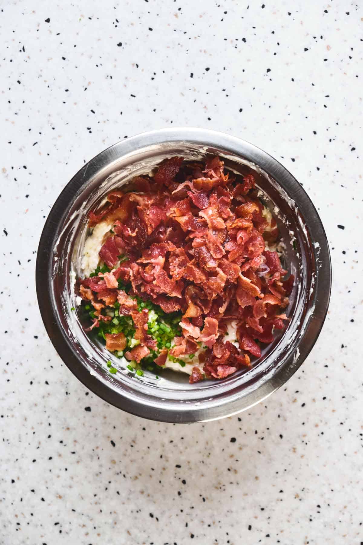 Mixing ingredients for baked bacon dip in a bowl.