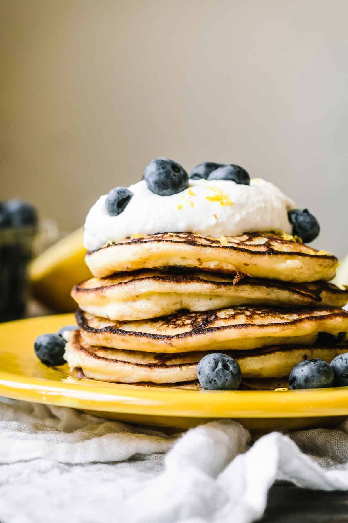 A stack of fluffy pancakes with a dollop of ricotta and fresh blueberries. 