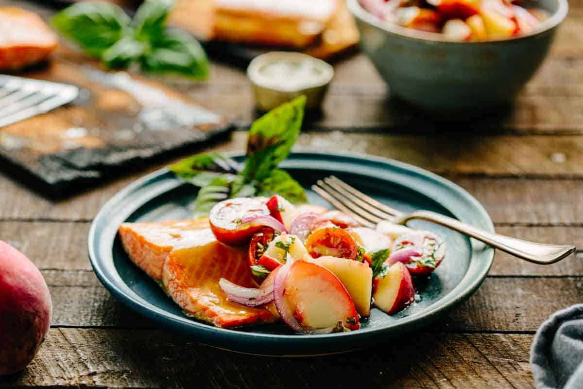A blue plate with a salmon fillet and tomato peach salsa.