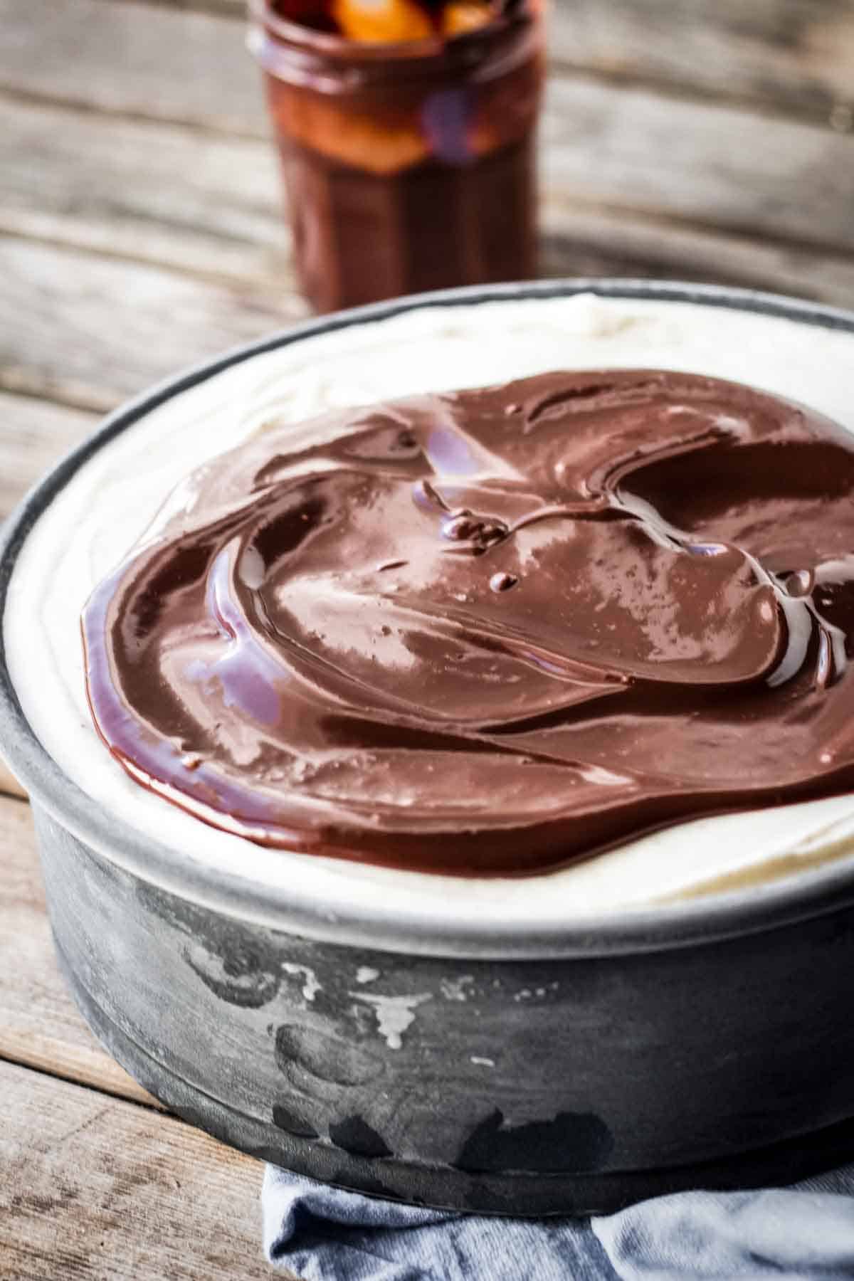 Spreading chocolate ganache on top of an ice cream cake.