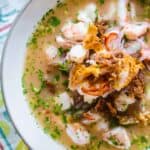 A white bowl filled with shrimp ceviche and fried plantains.