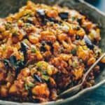 A serving bowl of caponata with raisins and pine nuts.